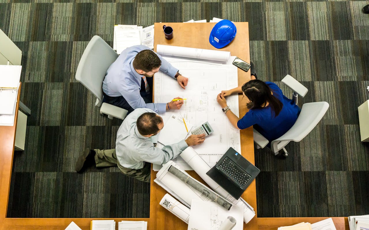 client-stories-img Top view of a team working on construction plans in an office setting.